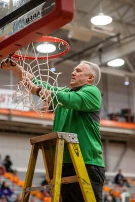 Woodinville head coach Scott Bullock takes down the net following the Falcons fourth consecutive district championship.